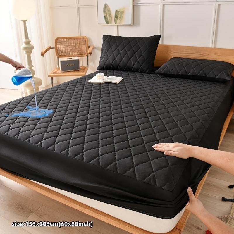 Waterproof ultra-soft black quilted mattress protector cover on bed.